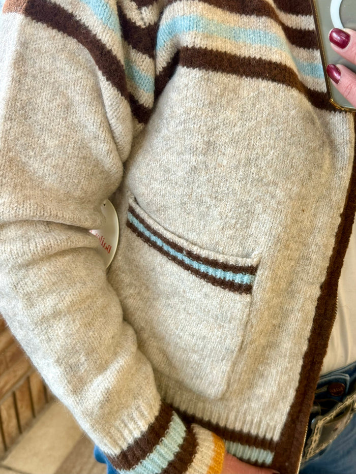 Tan knit cardigan with ribbed brown and light-blue stripe band and front pocket detail
