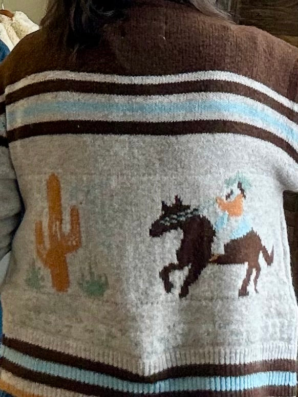 Close-up knit panel: horse and cactus motifs with brown, tan, and light-blue stripes