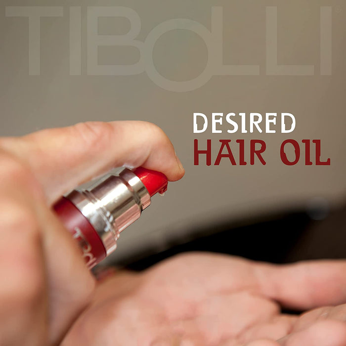 Hand pressing the pump of a red Tibolli bottle into a palm, with "Desired Hair Oil" and the Tibolli logo behind
