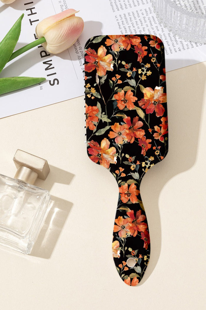Orange floral paddle hair brush with black bristles and long paddle back