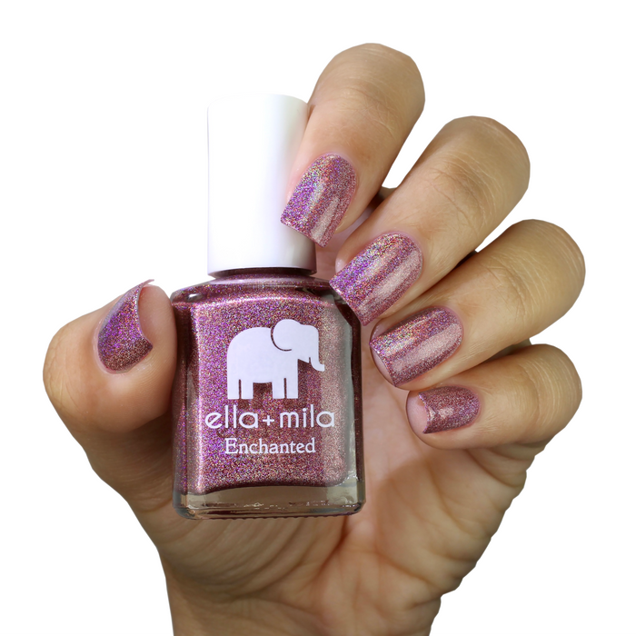 Dragonfly holographic fuchsia nail polish on a medium skin tone, hand holding the bottle