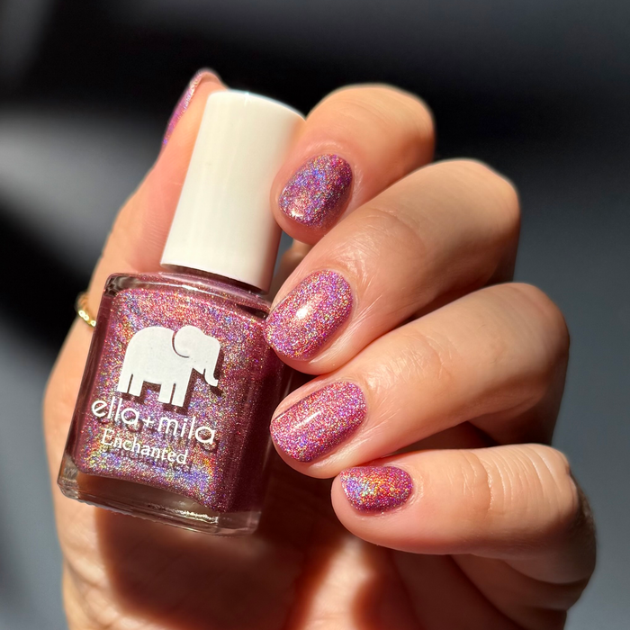 Dragonfly holographic fuchsia nail polish close-up on a light skin tone, holding the bottle