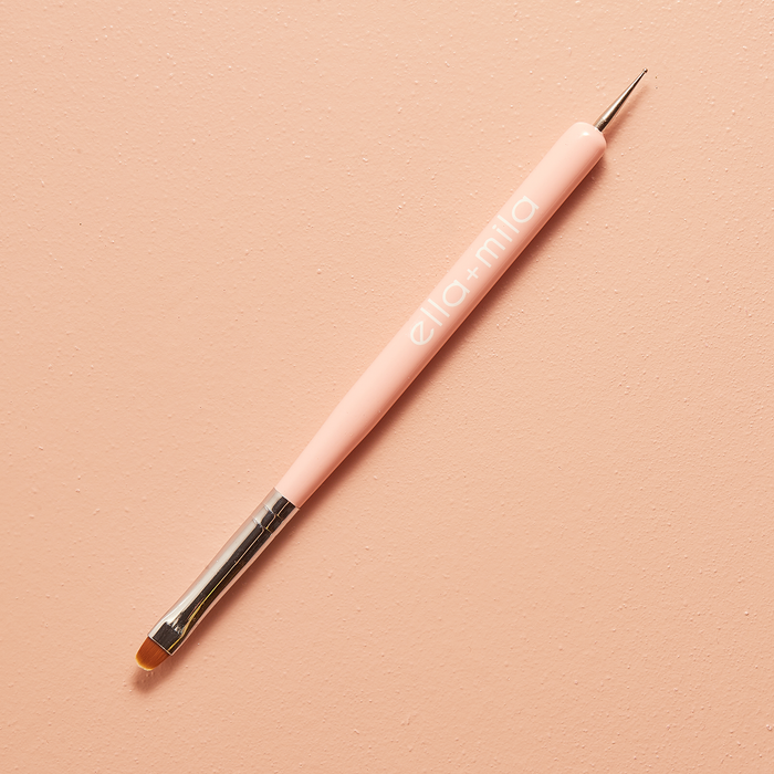 Dual-ended nail art dotter and detail brush on a peach background