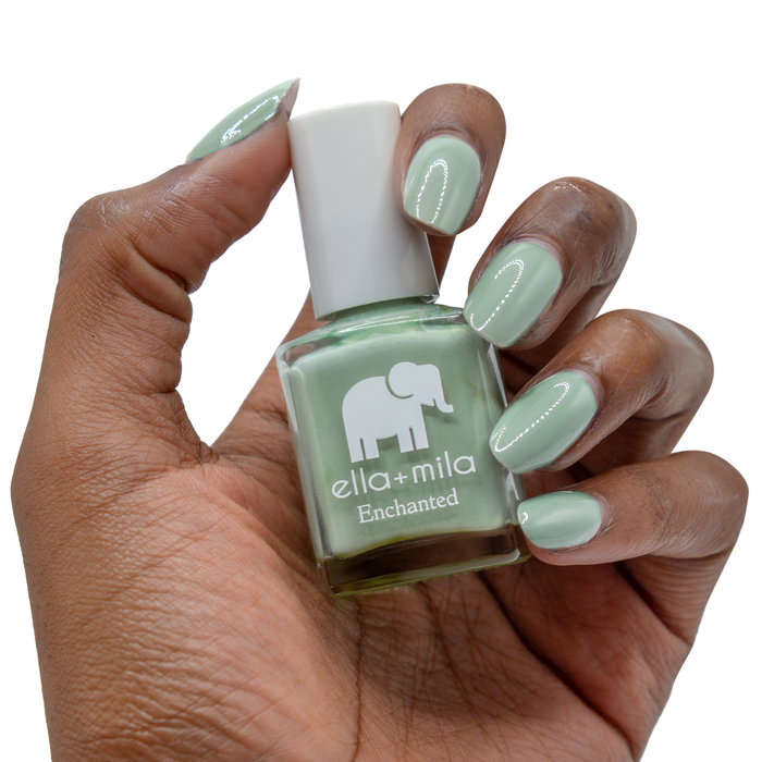 Evergreen muted green nail polish on a deep skin tone, hand holding the bottle