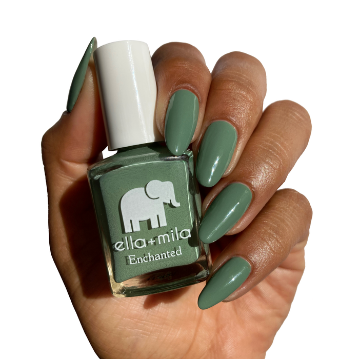 Evergreen muted green nail polish on a deep skin tone, holding the bottle
