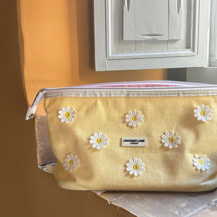 Expandable yellow makeup bag with white daisy embroidery and a zipper, Coconut Lane Buttercup Bloom edition.