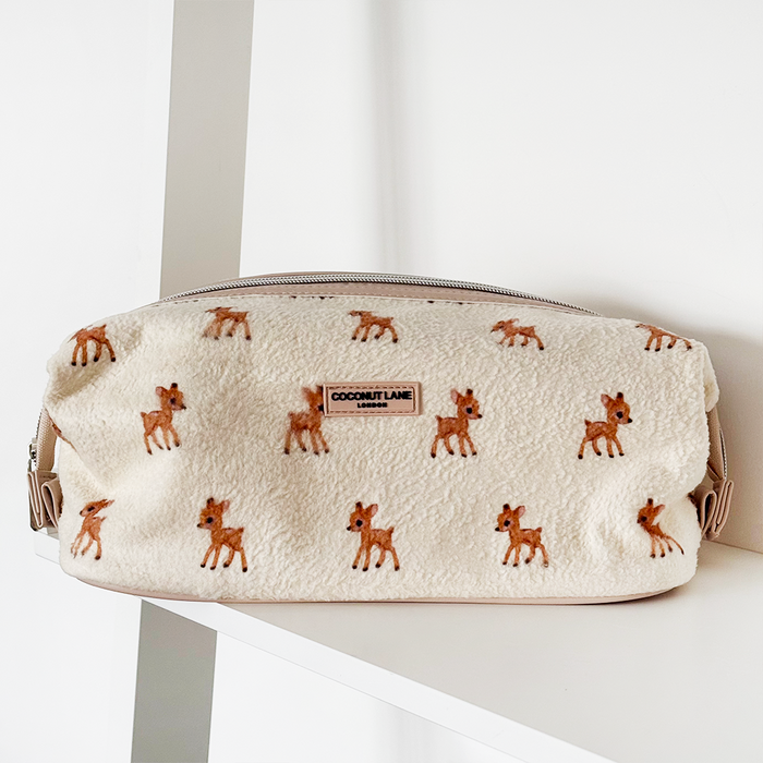 Cream Coconut Lane expandable makeup bag with deer pattern on a white shelf.