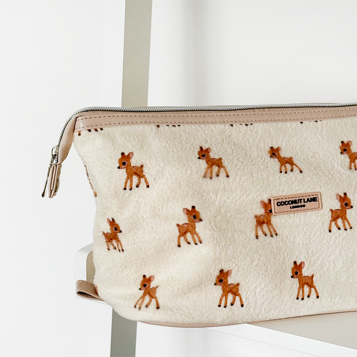 Fleecy Fawn expandable makeup bag by Coconut Lane, with zipper and logo label, displayed on a white shelf.