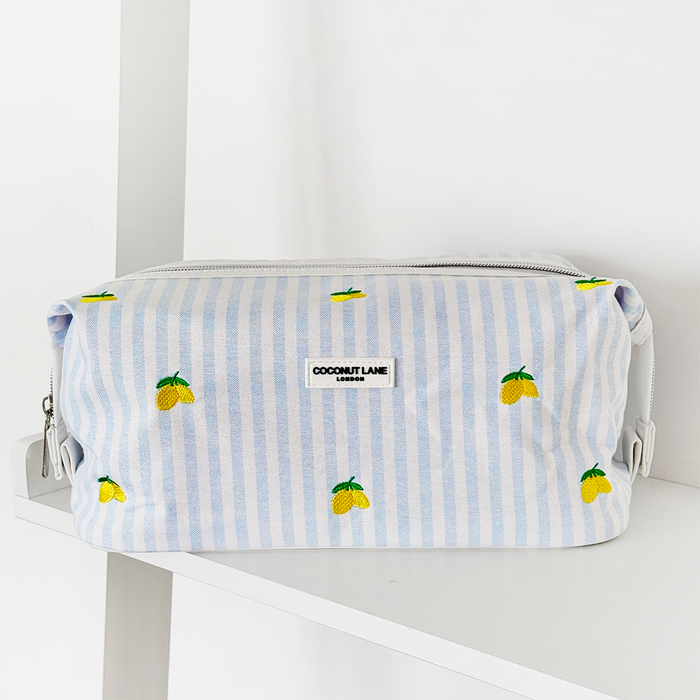 Yellow lemon-patterned expandable makeup bag from Coconut Lane on a white shelf.