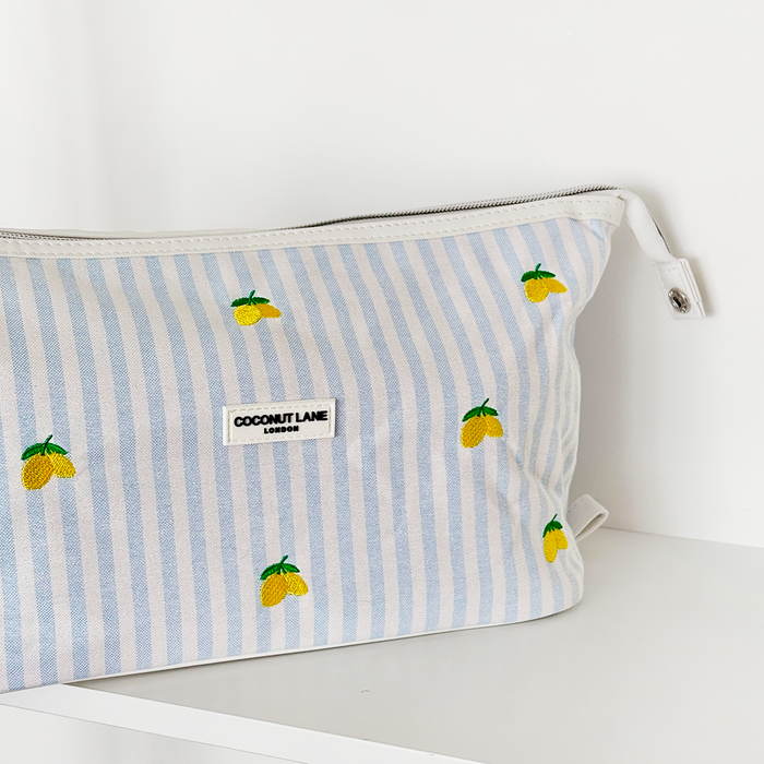 Expandable makeup bag with white and blue stripes, lemon embroidery, and a front label.