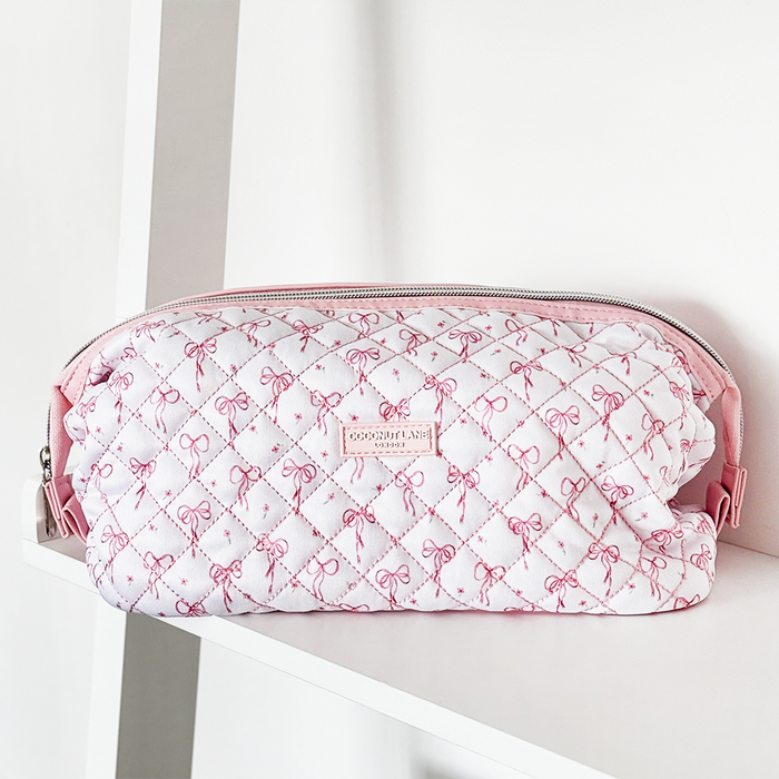 Expandable quilted makeup bag with pink bows and candy cane patterns on a light background.