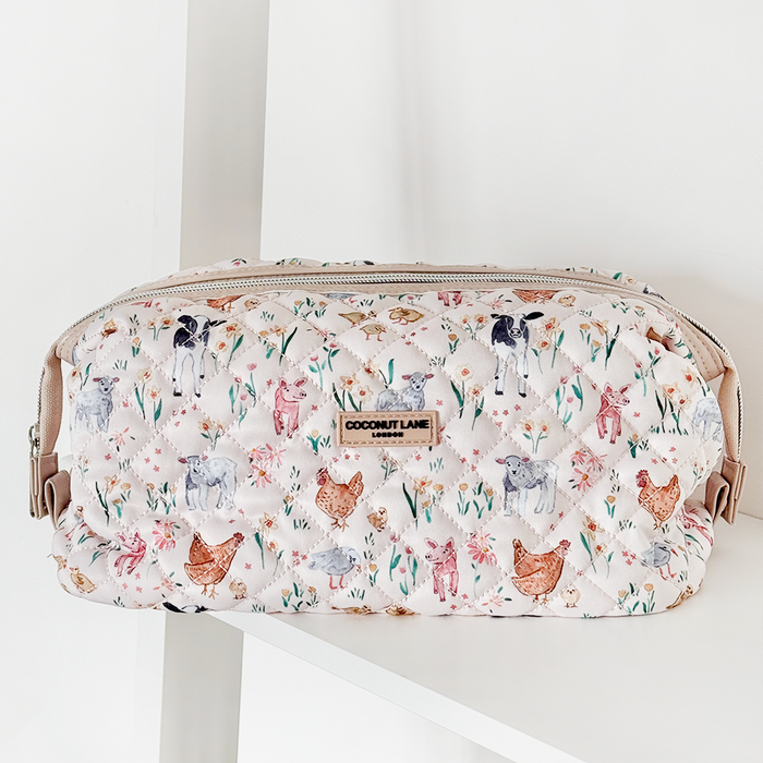 Quilted Coconut Lane expandable makeup bag with a farmyard animal print, displayed on a white shelf.
