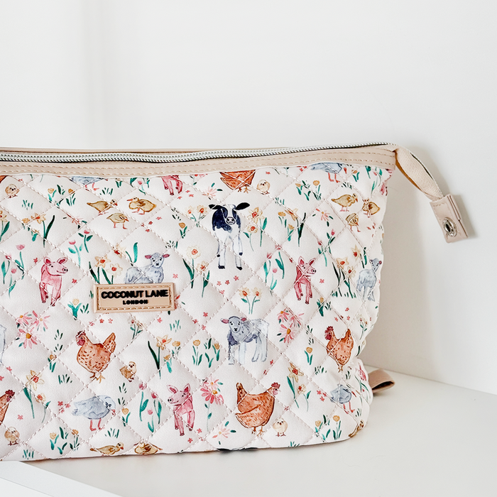 Quilted makeup bag with a farmyard animals pattern by Coconut Lane on a white shelf.