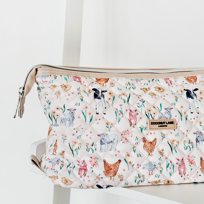 Quilted Coconut Lane expandable makeup bag with animal and floral print, beige zipper, on a white surface.