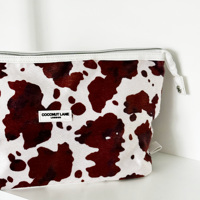Expandable makeup bag with a white and brown cow print pattern.