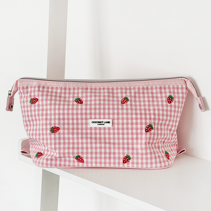 Pink gingham expandable makeup bag with strawberry print and a front label.