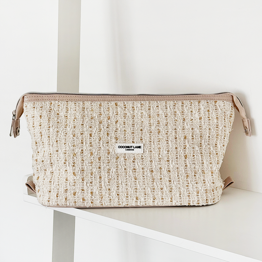 Vanilla textured tweed Coconut Lane expandable makeup bag displayed on a white shelf with a white background.