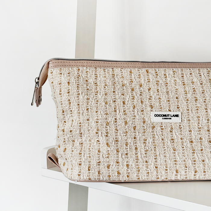 Vanilla tweed expandable makeup bag with zipper, by Coconut Lane, displayed on a white shelf.
