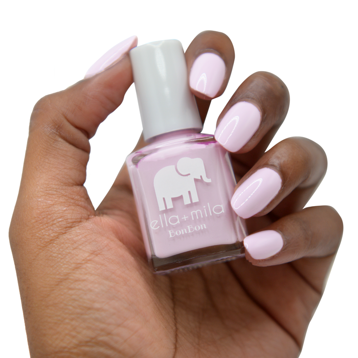Eye Candy light pastel purple nail polish on a deep skin tone, hand holding the bottle