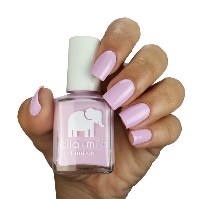 Eye Candy pastel purple nail polish on a medium skin tone, hand holding the bottle