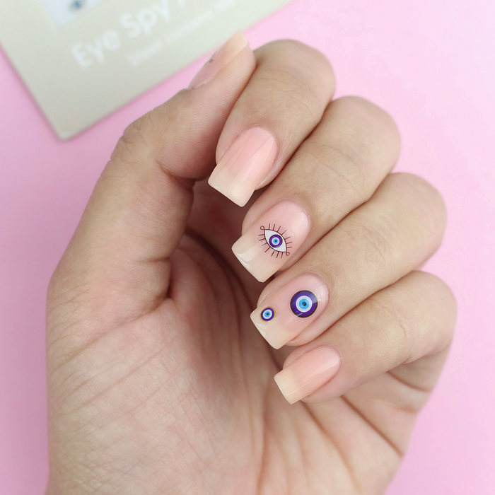 Eye Spy an Evil Eye decals on a sheer nude manicure with the packaging