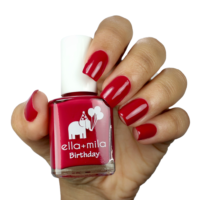 Fourth Wish true red nail polish on a medium skin tone, hand holding the bottle