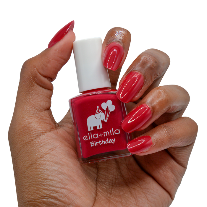 Fourth Wish true red nail polish on a deep skin tone, hand holding the bottle