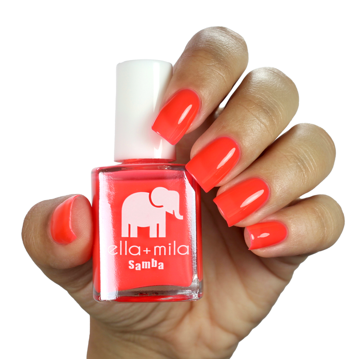 French Martini vibrant coral nail polish on a medium skin tone, hand holding the bottle
