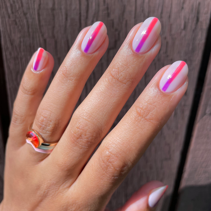 French Martini coral with neon stripe nail art on a light skin tone with a ring