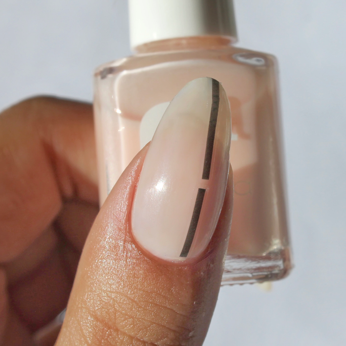 Get in Line black stripe decal on a sheer nude nail, holding the bottle