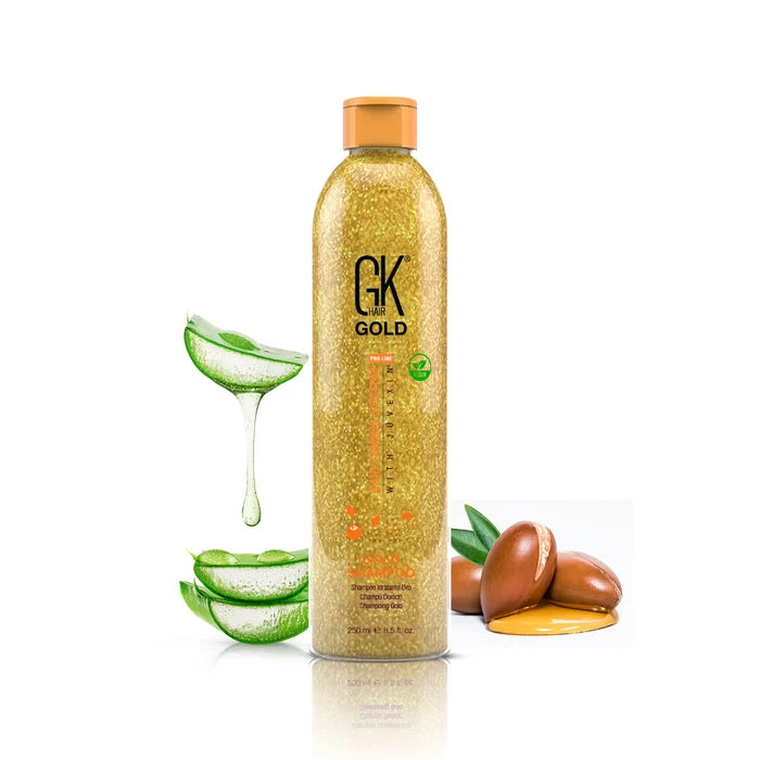 GK Hair Gold Shampoo 250 ml gold glitter bottle with an orange cap, beside dripping aloe vera slices and argan nuts in golden oil
