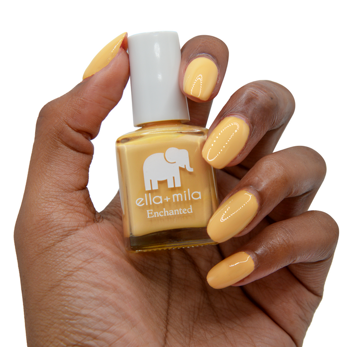 Goldie golden mustard nail polish on a deep skin tone, hand holding the bottle