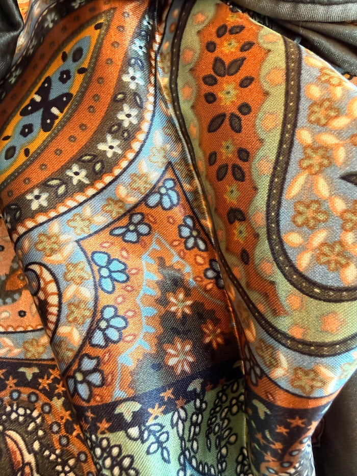 Paisley wild rag scarf fabric close-up in orange, blue, and dark green