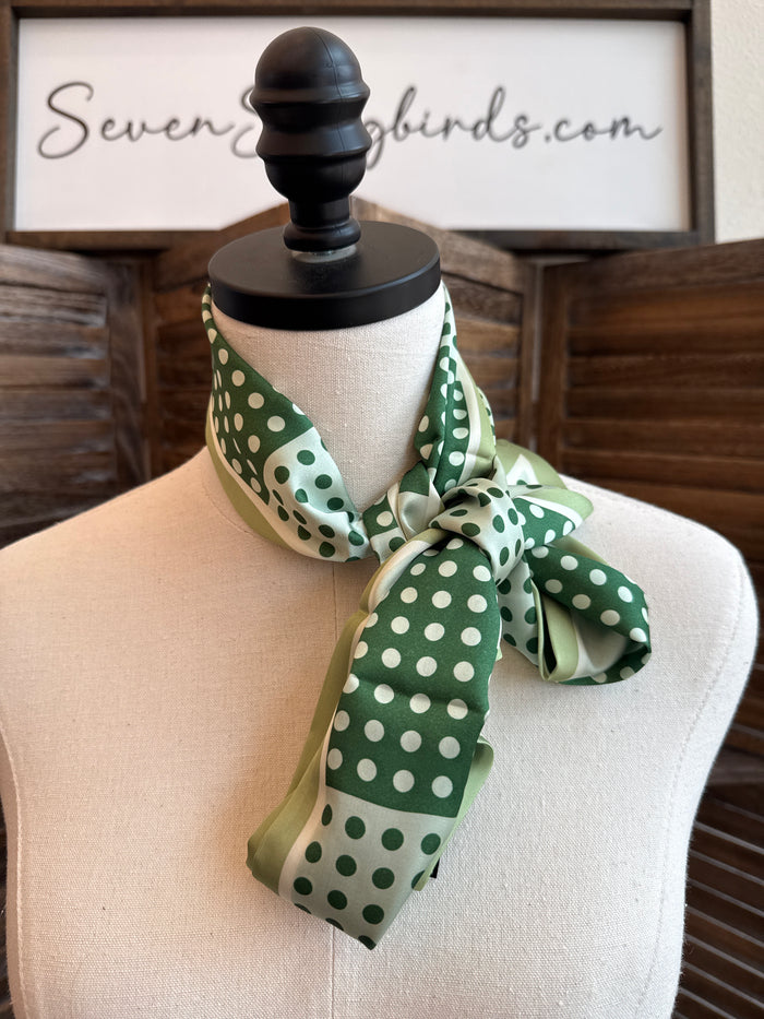 Green polka dot twilly scarf tied in a bow on a mannequin neck