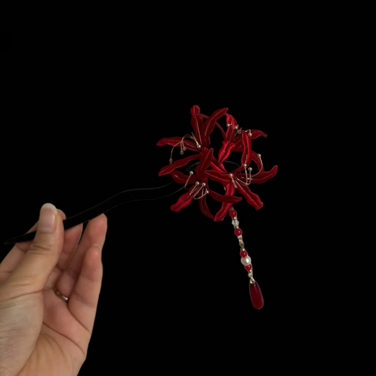 Close-up of an blue and red Chanhua thread-wrapped floral hair accessory with pearl accents.