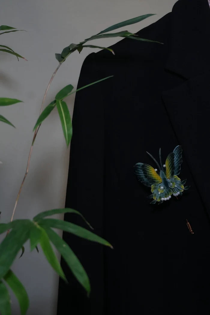 Handmade Ronghua antique-style butterfly brooch in teal and yellow mulberry silk velvet with pearl accents, pinned on black fabric