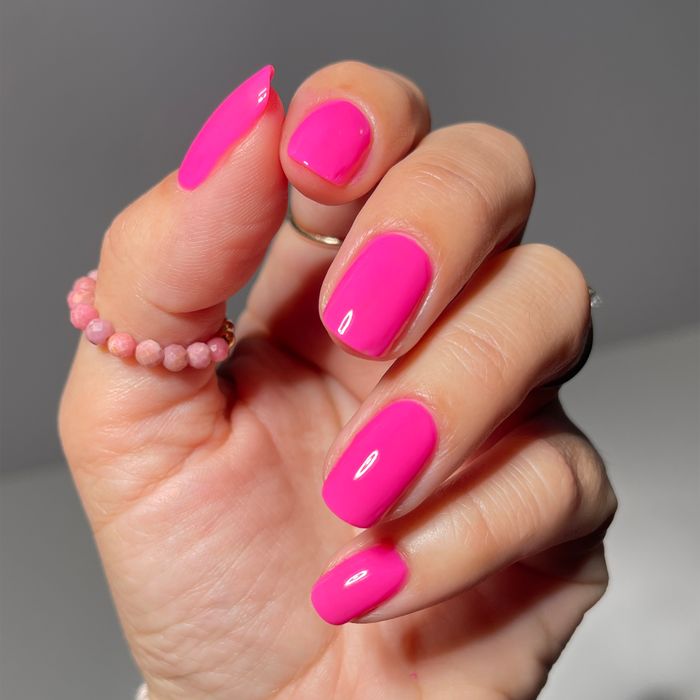 I Pink I Love You bright pink nail polish manicure on a medium skin tone with a beaded ring