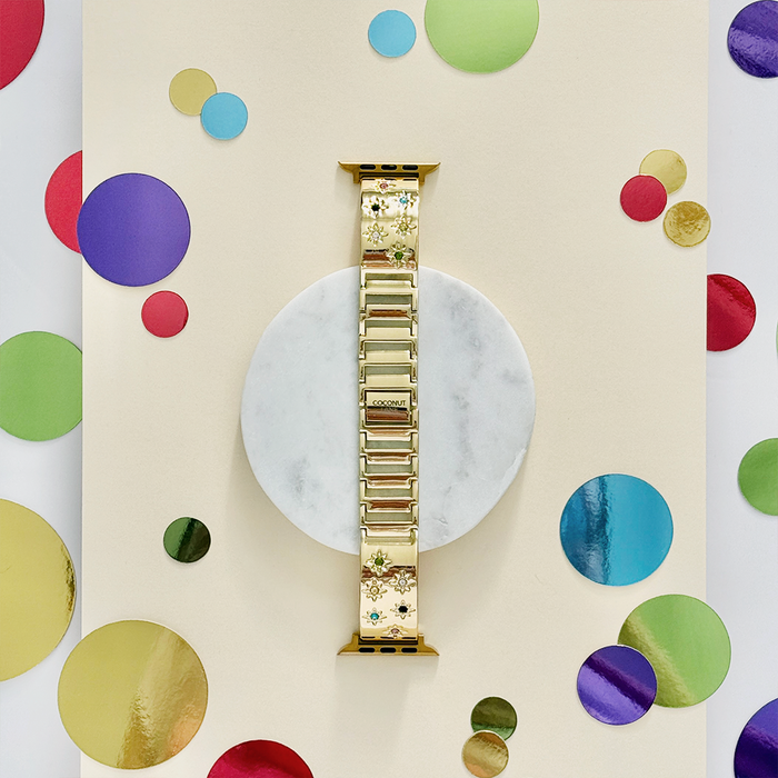 Gold Apple Watch strap with coloured stone accents, paired with a marble floral watch face featuring metallic confetti dots.