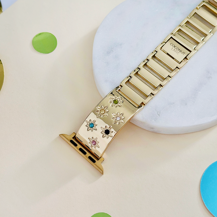 Gold Ibiza coloured stone Apple Watch strap by Coconut Lane resting on a dish with colorful confetti nearby.