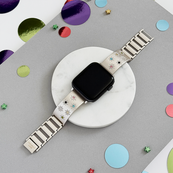 Starlight Coconut Lane Ibiza Apple Watch strap with coloured stones, shown on marble with confetti and geometric shapes.