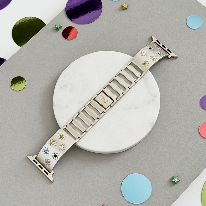 Coconut Lane Ibiza Apple Watch strap in Starlight with coloured stones, displayed on marble with confetti accents.