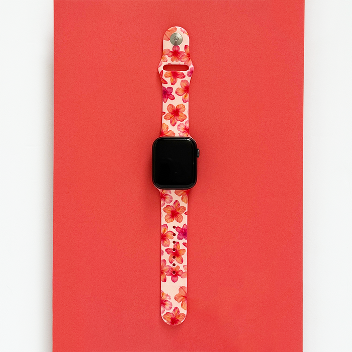 Pink hibiscus-patterned Apple Watch strap by Coconut Lane on a vibrant red background.