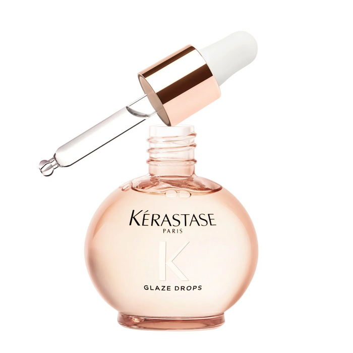 A bottle of Kerastase Gloss Absolu Glaze Drops Hair Oil with a dropper, showcasing the product in a clear, light pink liquid.