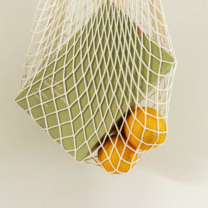 Net produce bag with box of laundry detergent sheets and lemons.
