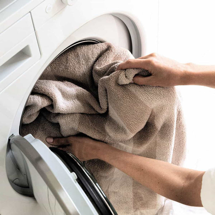 Person loading towels into a front loader washing machine.
