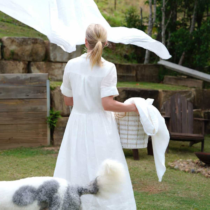 Woman in a white dress with a laundry basket, for bringing in clean sheets.