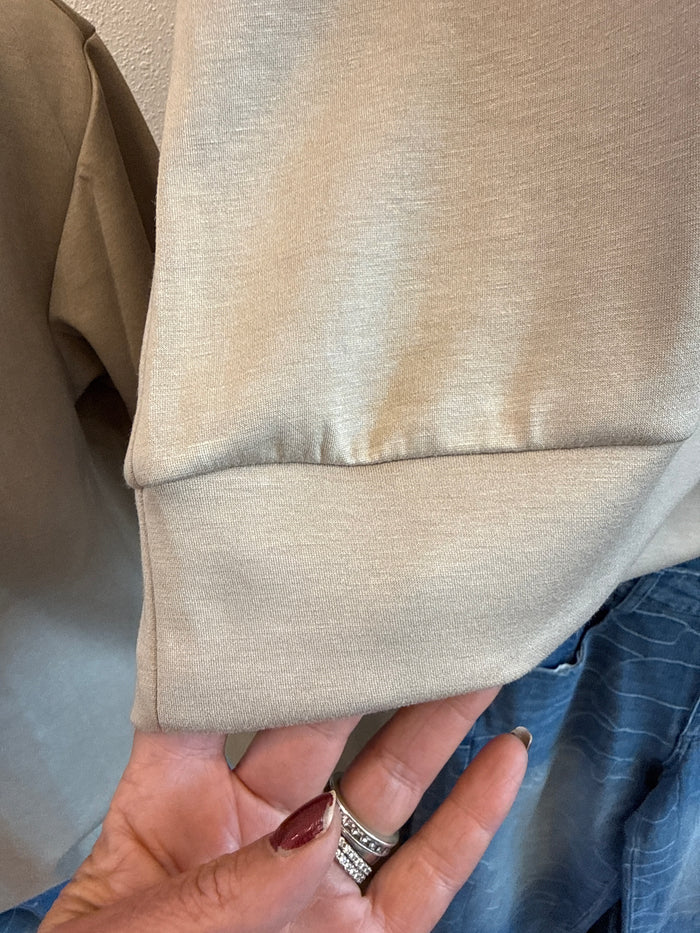 Sleeve cuff detail on a light taupe lightweight quarter-zip sweatshirt
