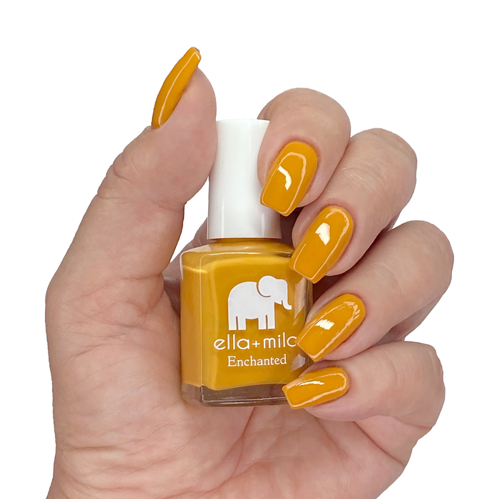 Lost City rustic mustard nail polish on a medium skin tone, hand holding the bottle