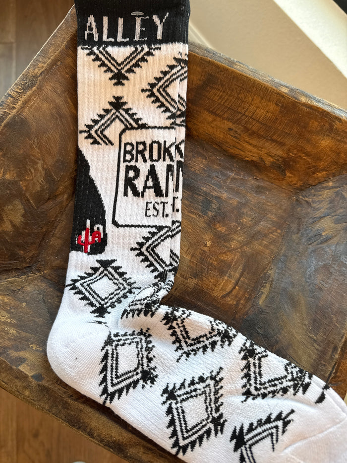 Performance socks in white with black geometric pattern and “Broke Ass Ranch” style print.