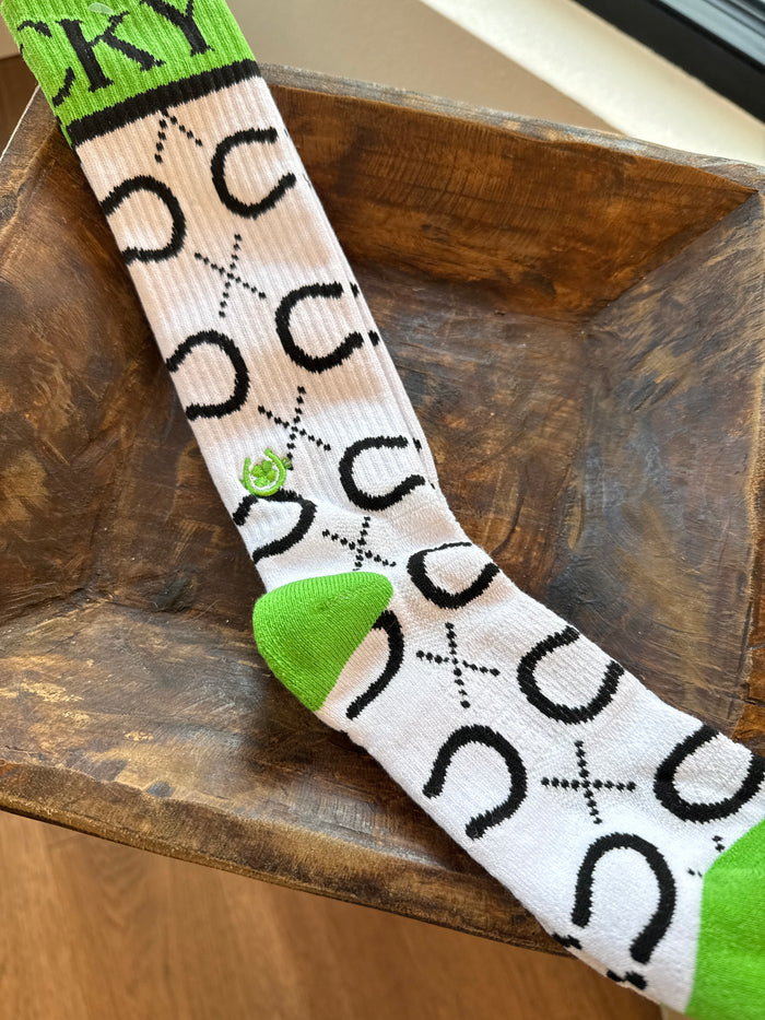 Performance socks in white with green cactus accents and black-and-white cross pattern.